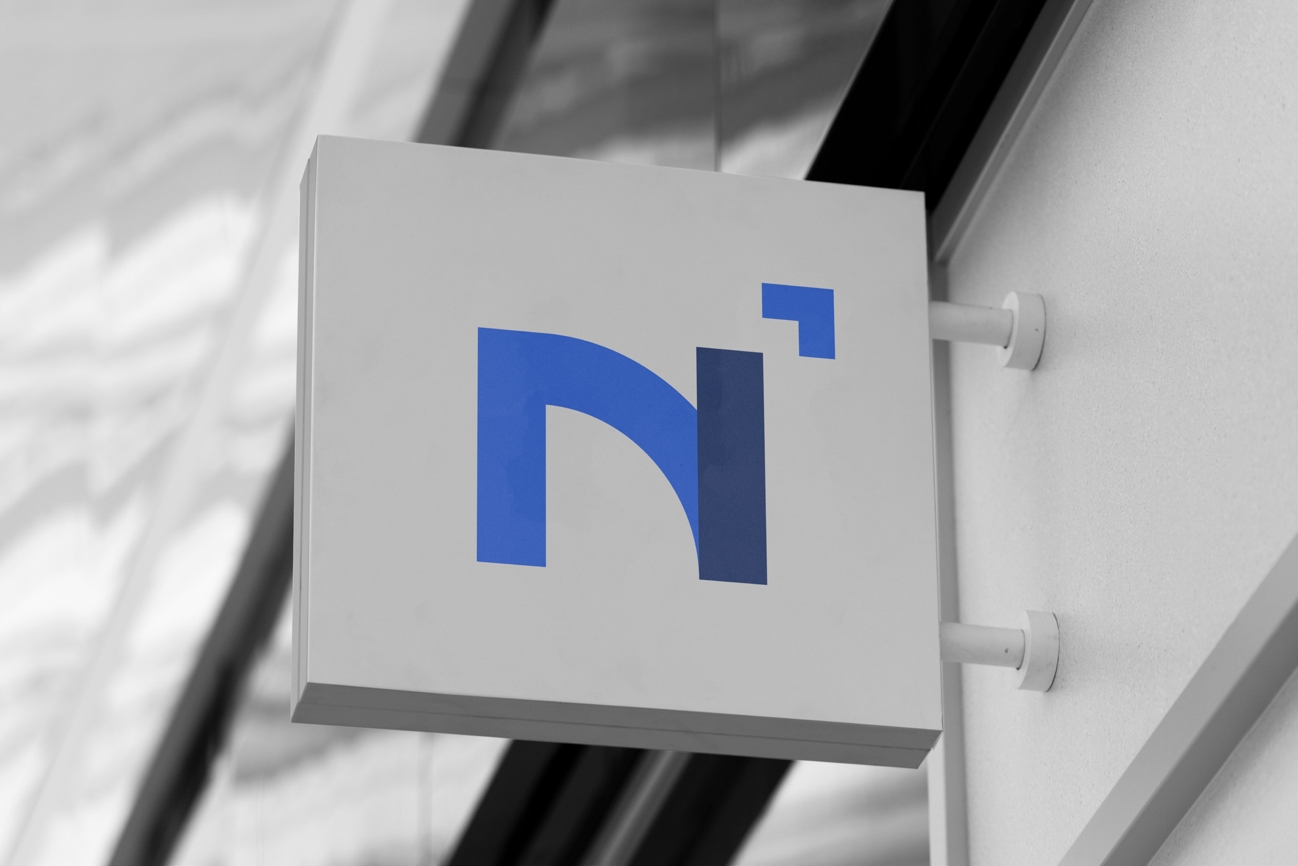 The INEED2 monogram on a storefront sign outside a modern building.